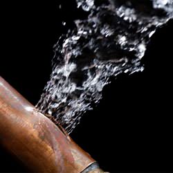 A bursting copper pipe in Lynn, with water gushing out.