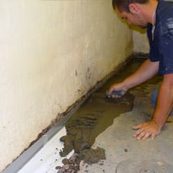 A basement waterproofer installing a perimeter drain system in Woburn