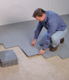 Contractors installing basement subfloor tiles and matting on a concrete basement floor in Lawrence, Massachusetts