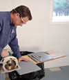 installing a waterproof vapor barrier on a basement floor to prepare for basement carpeting in a Lynn home